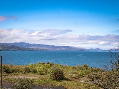 A coastal view with water shrubs and distant mountains at The Old Coastguard Tower Buncrana Buncrana County Donegal