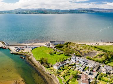A coastal village with houses green fields and a harbor on a bay with mountains in the background at The Old Coastguard Tower Buncrana County Donegal
