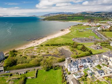 A coastal area with a beach parking lot houses and green fields at The Old Coastguard Tower Buncrana in Buncrana County Donegal