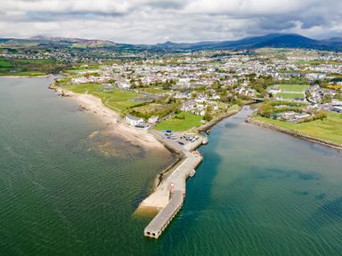 A coastal town with a pier extending into the water a sandy beach and residential area at The Old Coastguard Tower Buncrana County Donegal