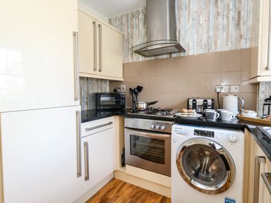 A kitchen with a washing machine oven microwave toaster kettle and cupboards at The Lobster Pot in Weymouth