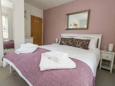 A bedroom with a double bed with folded towels on a purple throw at The Lobster Pot in Weymouth