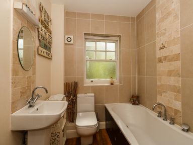 A bathroom with a sink mirror toilet and bathtub with tiles on the walls at The Lobster Pot in Weymouth