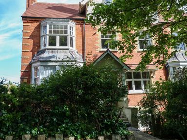 A brick house with bay windows and green bushes in front at The Lobster Pot in Weymouth