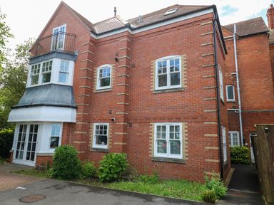 A red brick residential building with white windows and a small garden area at The Lobster Pot in Weymouth