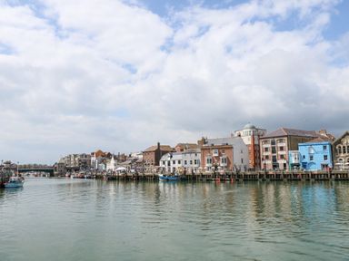 A harbor with boats docked along a waterfront with buildings and a bridge in the background at The Lobster Pot in Weymouth