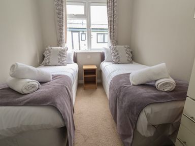 A bedroom with two single beds and towels on them at Lodge 4 in St Asaph
