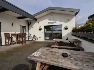 An outdoor seating area with wooden picnic tables and chairs in front of a building with a sign reading white spa at Lodge 4 in St Asaph