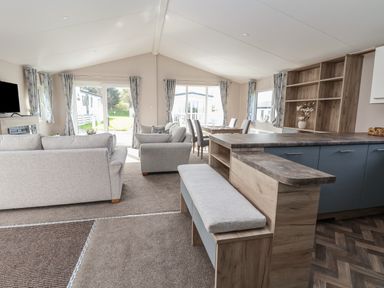 A living area with sofas a dining table chairs and a kitchen counter at Lodge 9 in St Asaph