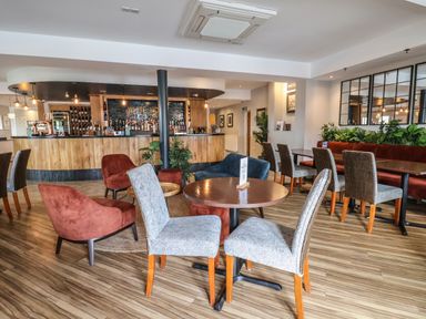 A bar area with tables and chairs and plants at Lodge 9 in St Asaph