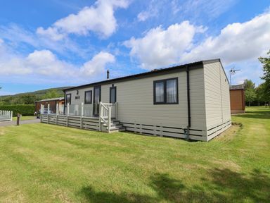 A mobile home with a deck and steps on a grass lawn at Lodge 9 in St Asaph