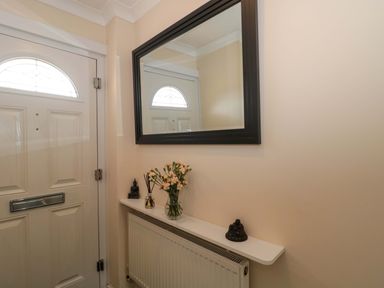 A hallway with a front door and a mirror at No 8 Burnham-on-Sea