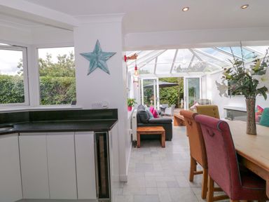 A conservatory with a dining area and seating area at No 8 Burnham-on-Sea