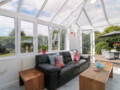 A conservatory with a sofa and coffee table at No 8 Burnham-on-Sea