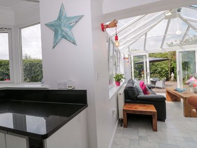 A conservatory with a sofa and coffee table at No 8 Burnham-on-Sea