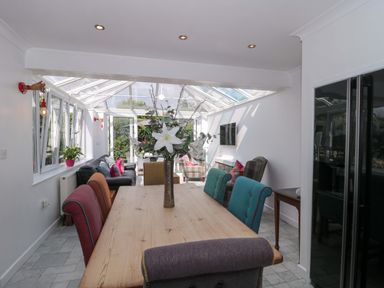 A conservatory with a dining table and seating area at No 8 Burnham-on-Sea