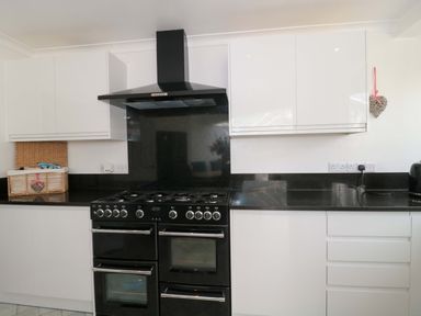 A kitchen with a black oven and white cabinets at No 8 Burnham-on-Sea