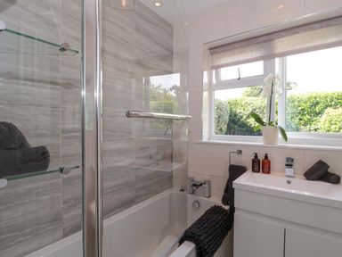 A bathroom with a bathtub and a glass shower at No 8 in Burnham-on-Sea