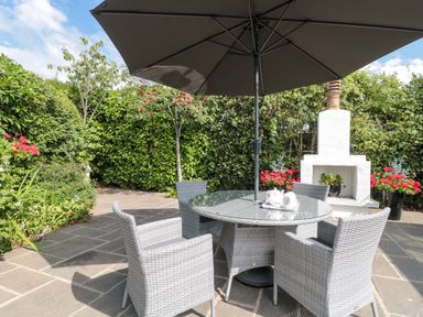 A garden with a table and chairs under an umbrella at No 8 Burnham-on-Sea