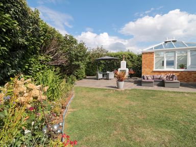 A garden with a conservatory and seating area at No 8 Burnham-on-Sea