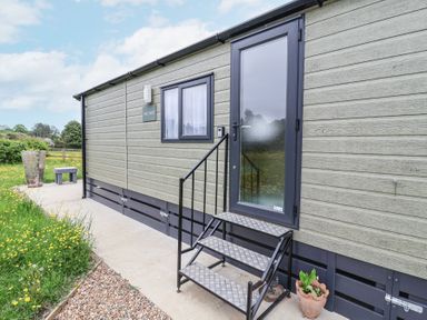 Exterior side view of a small building with steps leading to a frosted glass door and a small window at The Hoot Great Finborough near Stowmarket