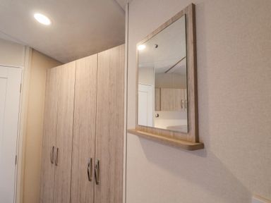A hallway with wooden wardrobes and a wall-mounted mirror at The Hoot in Great Finborough near Stowmarket