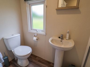 A bathroom with a toilet a sink a mirror and a window at The Hoot in Great Finborough near Stowmarket