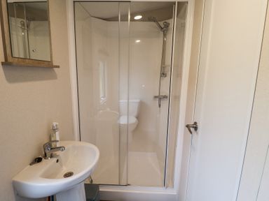 A bathroom with a pedestal sink soap dispenser mirrored cabinet shower enclosure and toilet reflected in the shower door at The Hoot in Great Finborough near Stowmarket