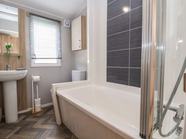 A bathroom with a bathtub shower sink toilet and window blinds at Woodlands Lodge in Bontuchel near Ruthin
