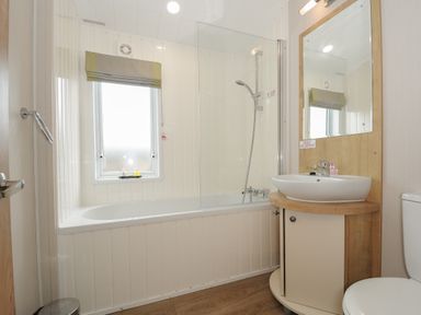 A bathroom with a bathtub shower combination sink with mirror and toilet at Lodge 67 at Riviera Bay Coastal Retreat in Brixham