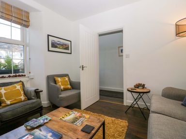 A living room with two armchairs a sofa a wooden coffee table and a side table at Acorn Cottage in Windermere
