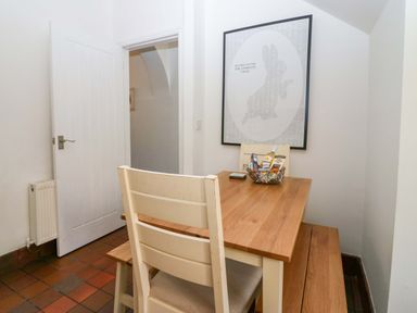 A small dining area with wooden table chairs and a bench a framed picture on the wall at Acorn Cottage in Windermere