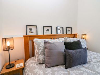 A bed with pillows and framed pictures on the headboard at Acorn Cottage in Windermere