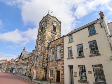 A street view with a clock tower and adjacent buildings at The Wizards Chamber in Alnwick