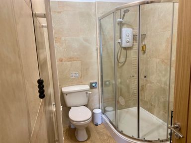A bathroom with a toilet and a curved glass shower enclosure at The Wizards Chamber in Alnwick