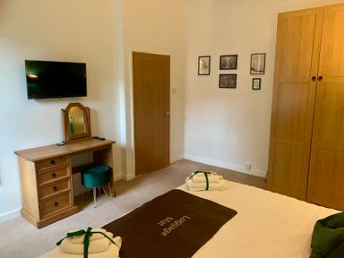 A bedroom with a wooden wardrobe desk and a wall-mounted television at The Wizards Chamber in Alnwick