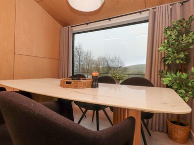 A dining area with a marble table black chairs a large window with curtains and a potted plant at Encil Gyfrinfa in Gwynus near Llithfaen