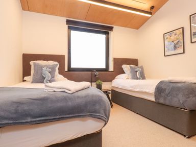 A bedroom with two single beds with blue and white bedding and seahorse cushions at Encil Gyfrinfa in Gwynus near Llithfaen