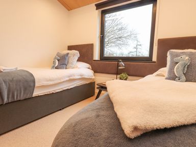 A bedroom with two single beds a window and a small table between the beds at Encil Gyfrinfa in Gwynus near Llithfaen
