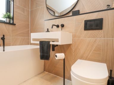 A bathroom with a bathtub sink toilet and geometric wall tiles at Encil Gyfrinfa in Gwynus near Llithfaen