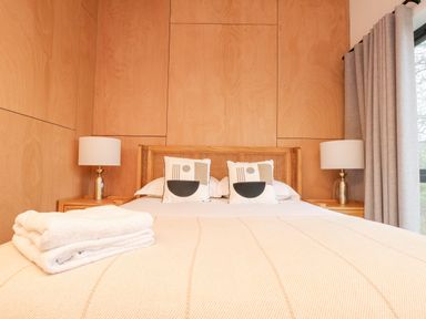 A bedroom with a bed and two pillows two bedside tables with lamps and folded towels on the bed at Encil Gyfrinfa in Gwynus near Llithfaen