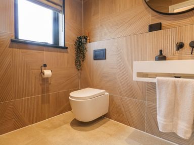 A bathroom with a wall-mounted toilet a white sink with towel and a window at Encil Gyfrinfa in Gwynus near Llithfaen
