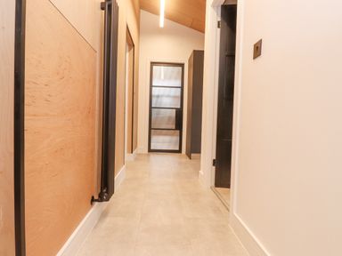 A hallway with a frosted glass door at the end and light-colored tiled floor at Encil Gyfrinfa in Gwynus near Llithfaen