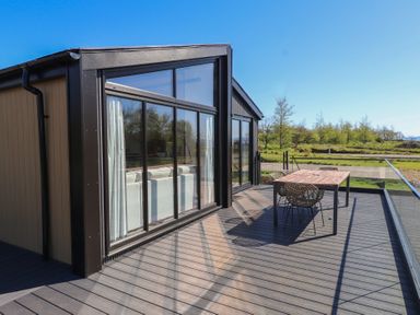 An outdoor area with a wooden table and chairs at Encil Gyfrinfa in Gwynus, near Llithfaen