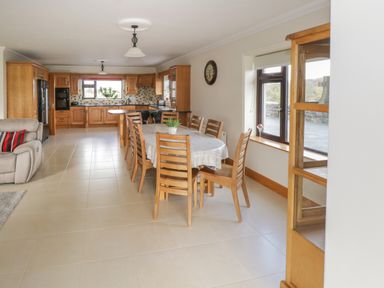 A dining area with a wooden table and chairs next to a kitchen with wooden cabinets at Bunny Lane in Cloonflynn near Ballycarra County Mayo