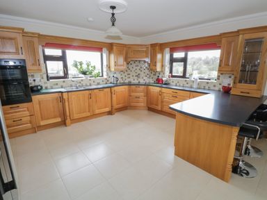 A kitchen with wooden cabinets black countertops tiled backsplash and two windows at Bunny Lane in Cloonflynn near Ballycarra County Mayo