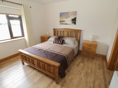 A bedroom with a wooden bed and two wooden nightstands with lamps at Bunny Lane in Cloonflynn near Ballycarra County Mayo
