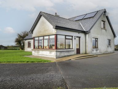 A house with multiple windows and a door with solar panels on the roof and grass surrounding it at Bunny Lane in Cloonflynn near Ballycarra County Mayo