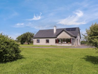 A detached house with solar panels on the roof surrounded by a grassy lawn and bushes at Bunny Lane in Cloonflynn near Ballycarra County Mayo