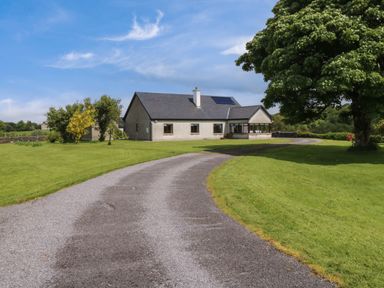 A single story house with a curved gravel driveway surrounded by grass and trees at Bunny Lane in Cloonflynn near Ballycarra County Mayo